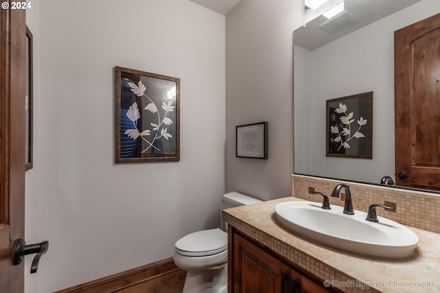 bathroom featuring hardwood / wood-style flooring, vanity, toilet, and tasteful backsplash