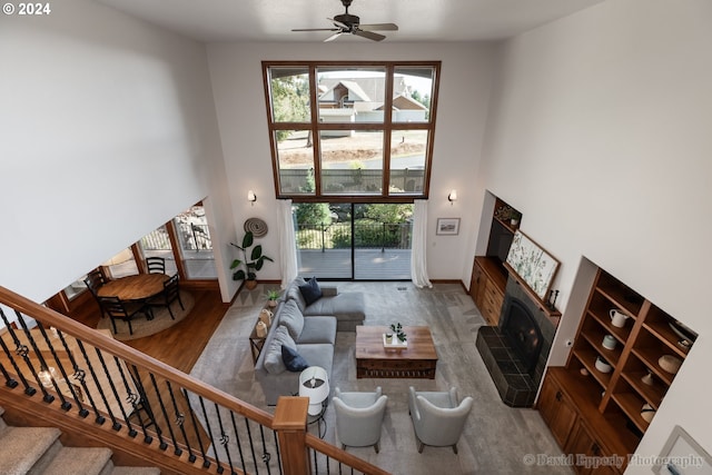 living room with light wood-type flooring, ceiling fan, and a stone fireplace