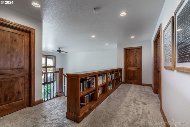 corridor with light carpet and a textured ceiling