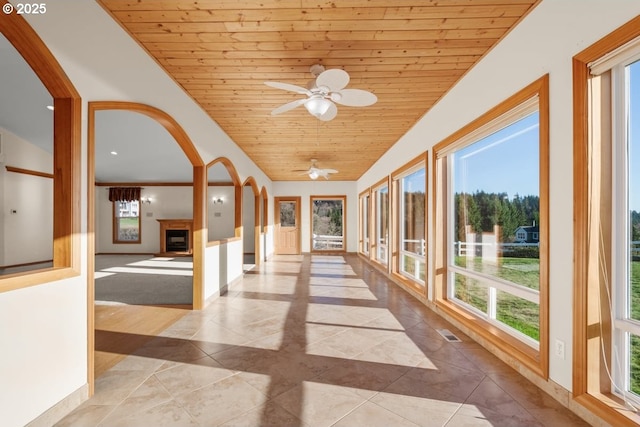 unfurnished sunroom featuring lofted ceiling, ceiling fan, and wood ceiling