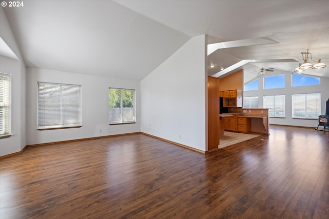 unfurnished living room with ceiling fan with notable chandelier, dark wood-type flooring, and lofted ceiling