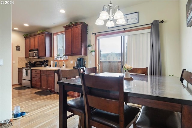 dining area featuring sink, light hardwood / wood-style flooring, and a chandelier