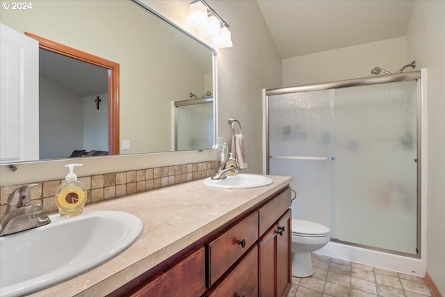 bathroom with vanity, vaulted ceiling, toilet, and a shower with shower door