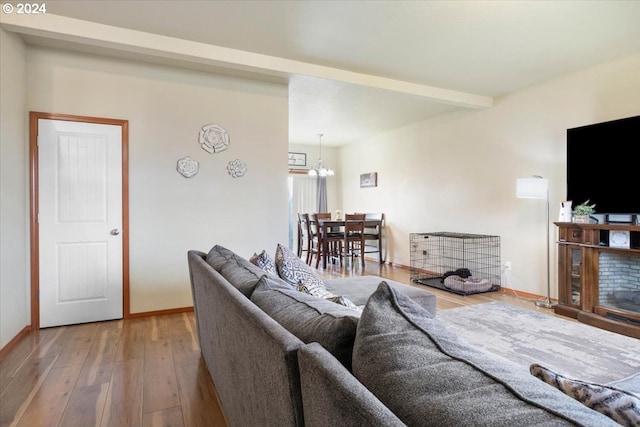 living room featuring beamed ceiling, a notable chandelier, and wood-type flooring