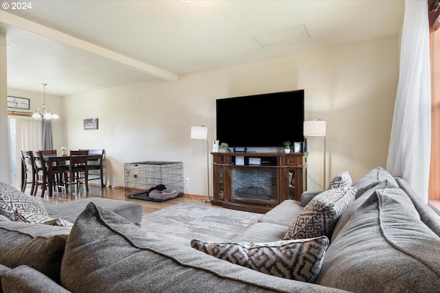 living room featuring beam ceiling, a fireplace, hardwood / wood-style floors, and an inviting chandelier