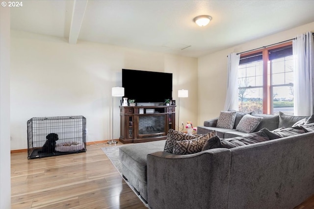 living room with hardwood / wood-style floors, beam ceiling, and a fireplace