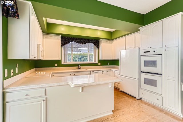 kitchen featuring white appliances, light hardwood / wood-style flooring, white cabinetry, and sink