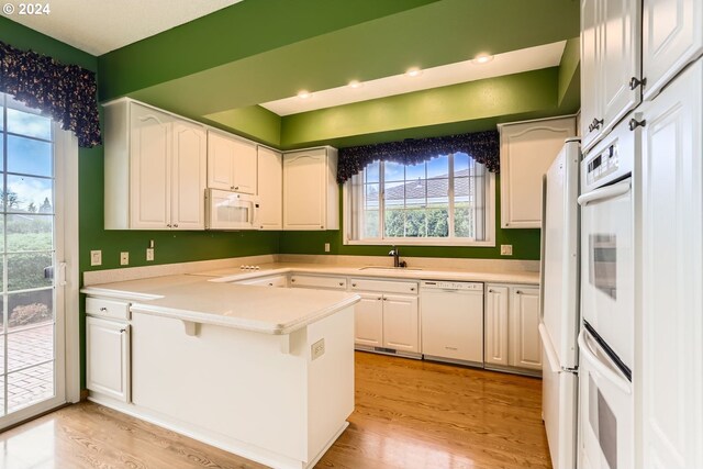 kitchen with white cabinets, a healthy amount of sunlight, white appliances, and light wood-type flooring