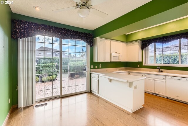 kitchen with white cabinets, light wood-type flooring, and white appliances