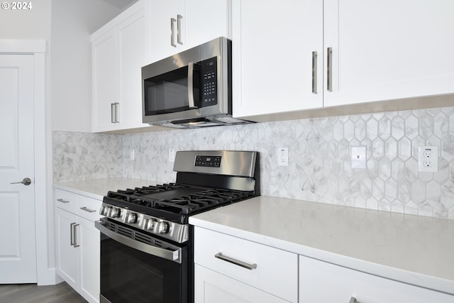 kitchen with wood-type flooring, stainless steel appliances, backsplash, light stone countertops, and white cabinetry