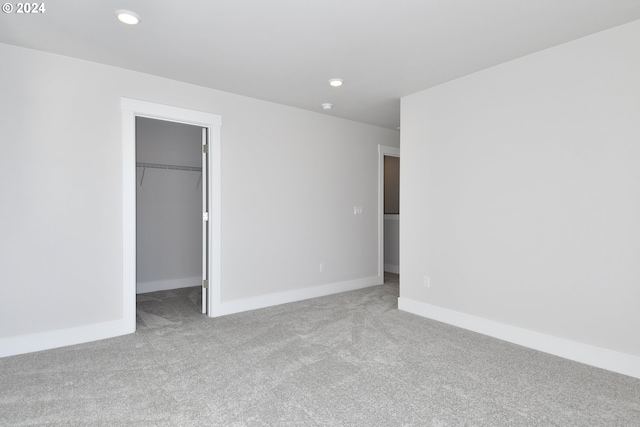 unfurnished bedroom featuring light carpet, a closet, and a spacious closet