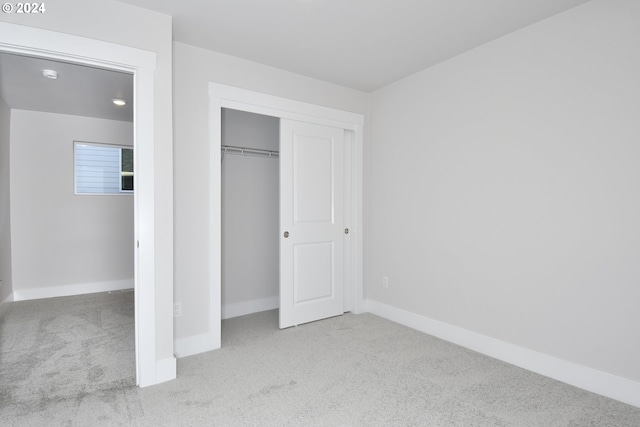 unfurnished bedroom featuring a closet and light colored carpet