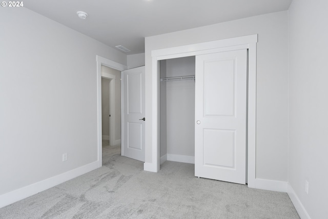 unfurnished bedroom featuring light carpet and a closet