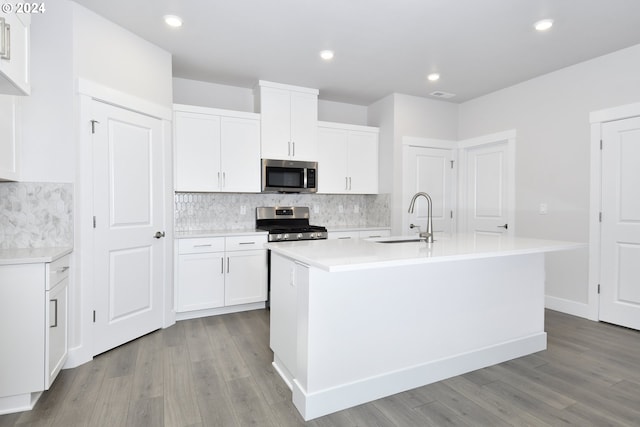 kitchen with white cabinetry, appliances with stainless steel finishes, sink, and a kitchen island with sink