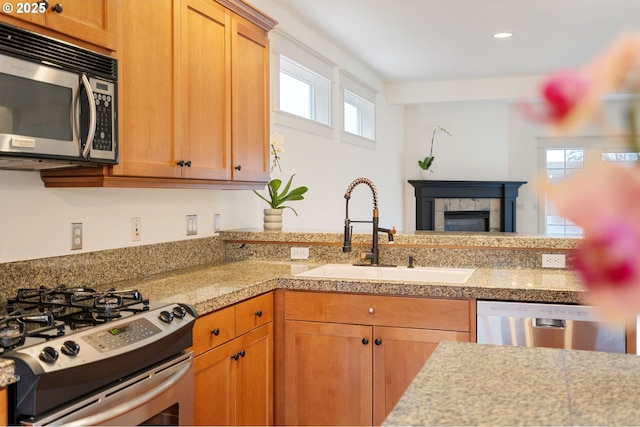 kitchen with sink, stainless steel appliances, and a tiled fireplace