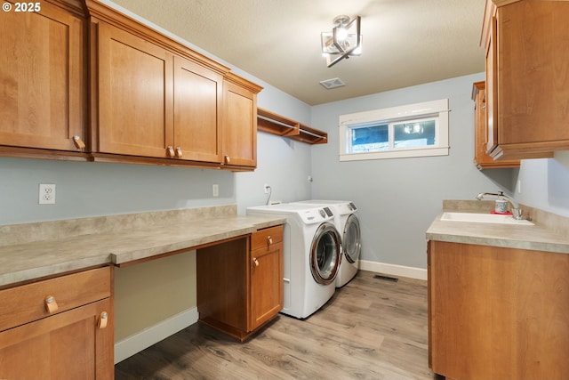 clothes washing area featuring sink, separate washer and dryer, light hardwood / wood-style floors, and cabinets