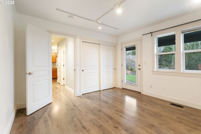 interior space featuring wood-type flooring, access to exterior, a closet, and rail lighting