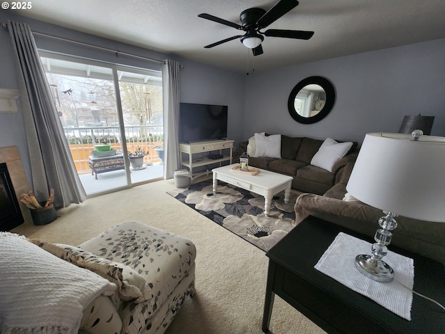 carpeted living room with a tiled fireplace and ceiling fan