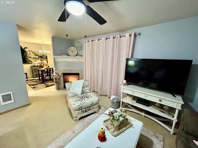 living room with carpet flooring, ceiling fan with notable chandelier, and a textured ceiling