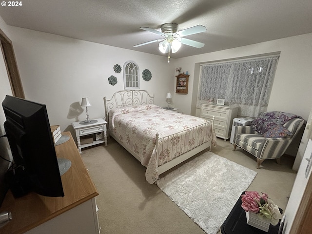 bedroom featuring a textured ceiling, light colored carpet, and ceiling fan