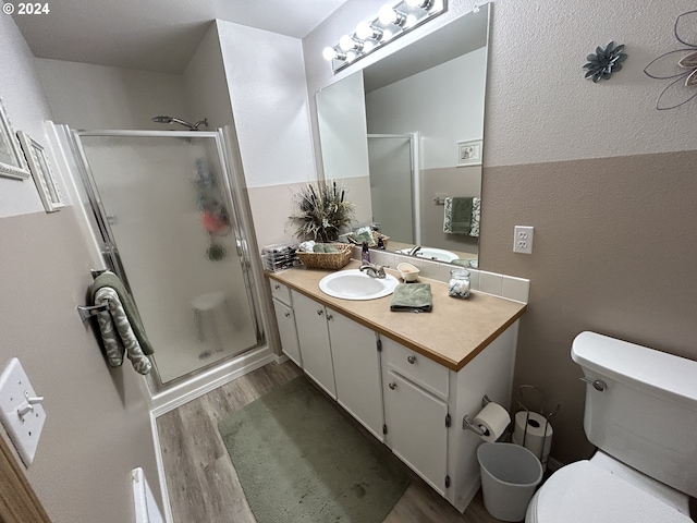 bathroom featuring hardwood / wood-style floors, toilet, vanity, and walk in shower