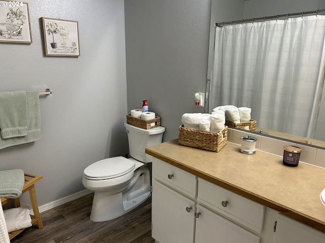 bathroom featuring hardwood / wood-style flooring, vanity, toilet, and curtained shower