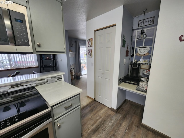 kitchen with appliances with stainless steel finishes, dark hardwood / wood-style flooring, and gray cabinetry