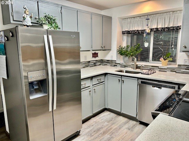 kitchen featuring gray cabinetry, sink, light wood-type flooring, and appliances with stainless steel finishes