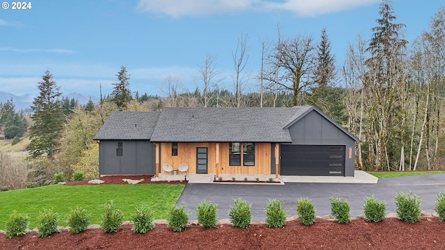 view of front of home with driveway, an attached garage, a front lawn, and a shingled roof