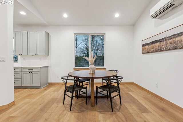 dining room with light hardwood / wood-style floors and a wall mounted AC