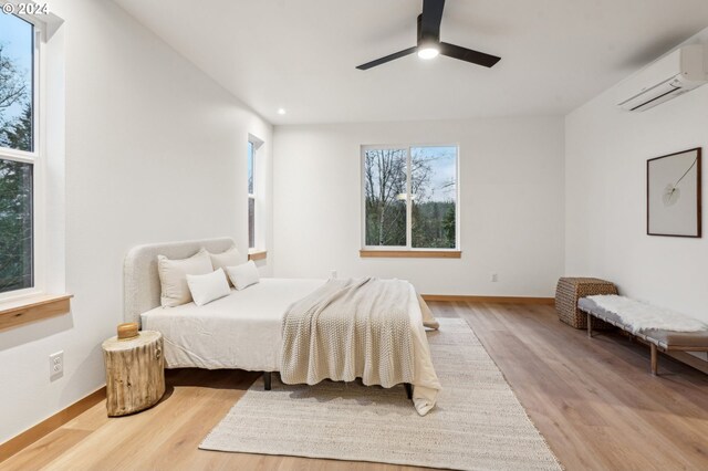 bedroom featuring hardwood / wood-style floors, ceiling fan, and a wall mounted AC