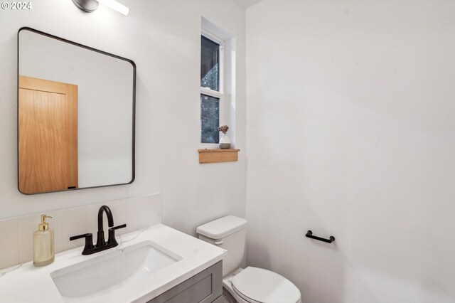 bathroom featuring decorative backsplash, vanity, and toilet