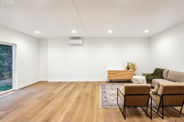 living area with hardwood / wood-style flooring and an AC wall unit