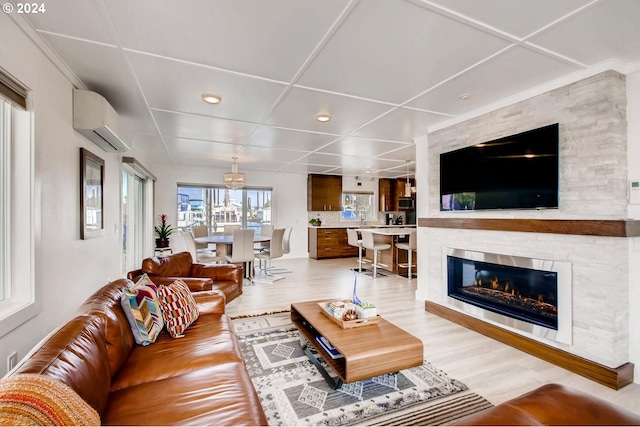 living room with a wall mounted AC, sink, a fireplace, and light hardwood / wood-style flooring