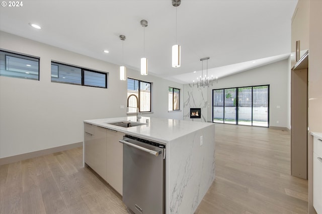 kitchen featuring white cabinetry, sink, stainless steel dishwasher, pendant lighting, and a kitchen island with sink