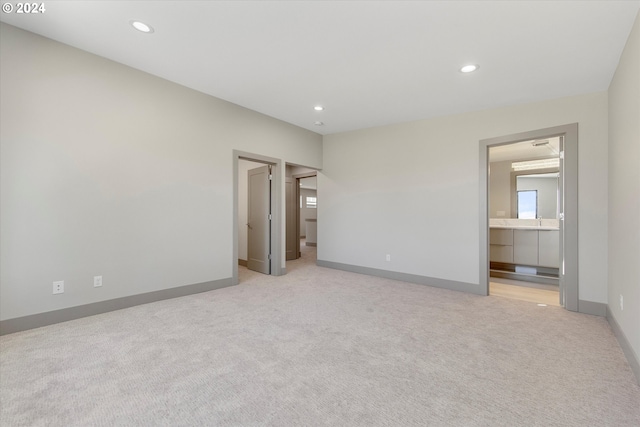 unfurnished bedroom featuring light carpet and connected bathroom