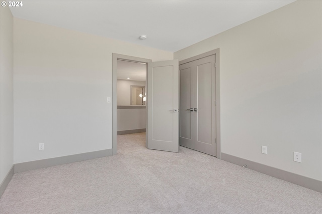 unfurnished bedroom with light colored carpet and a closet