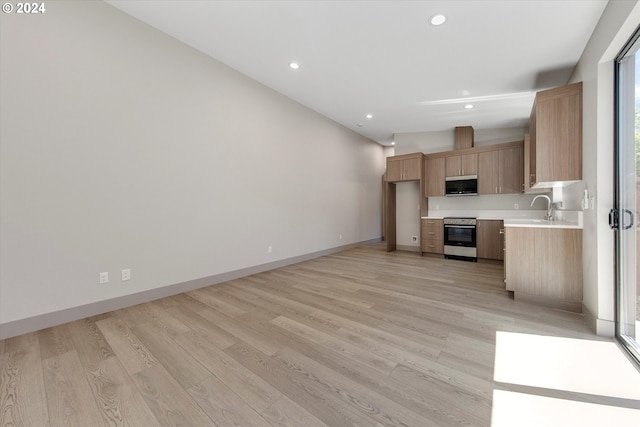 kitchen featuring light brown cabinets, plenty of natural light, light hardwood / wood-style floors, lofted ceiling, and electric stove