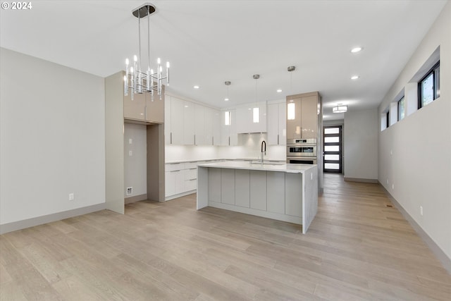 kitchen featuring light hardwood / wood-style flooring, white cabinets, decorative light fixtures, and sink