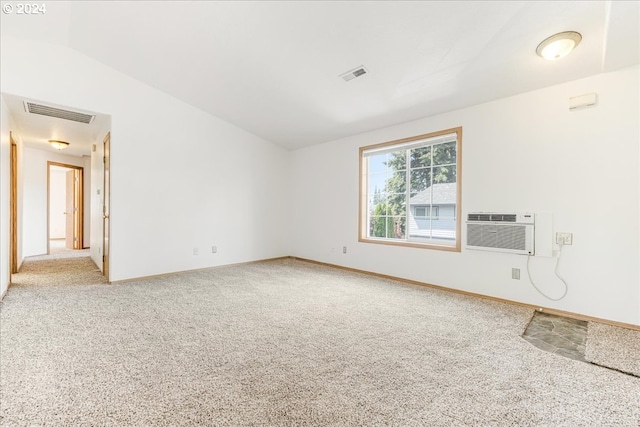 empty room with a wall mounted air conditioner, vaulted ceiling, and carpet flooring