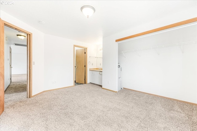 unfurnished bedroom with light colored carpet, a closet, and ensuite bathroom