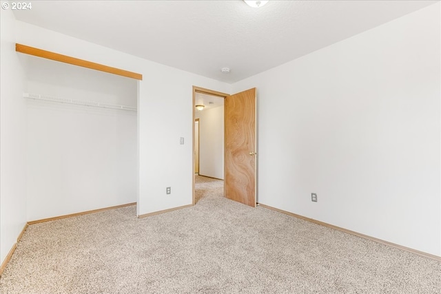 unfurnished bedroom featuring a closet and light carpet