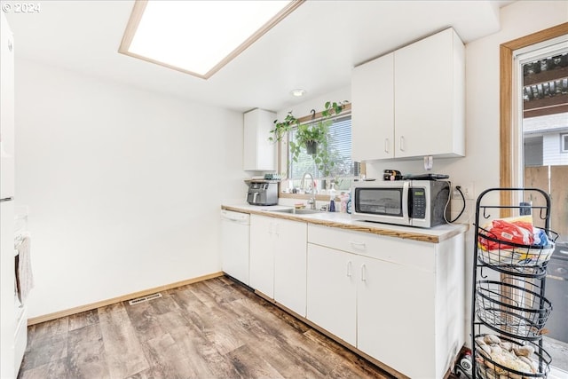 kitchen featuring sink, white cabinets, light wood-type flooring, and dishwasher