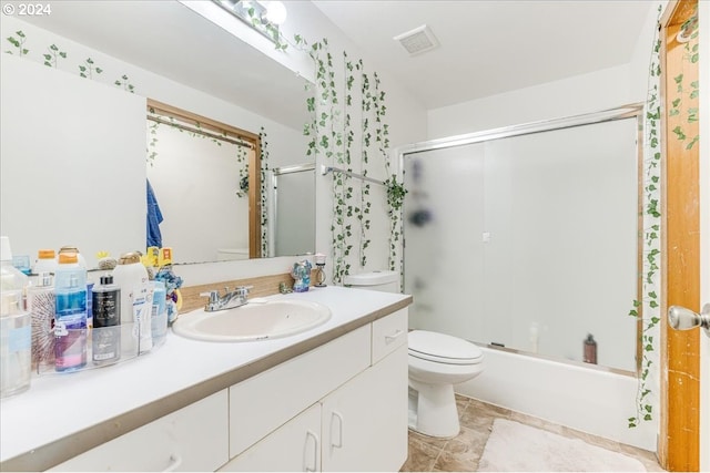 full bathroom featuring toilet, enclosed tub / shower combo, and vanity