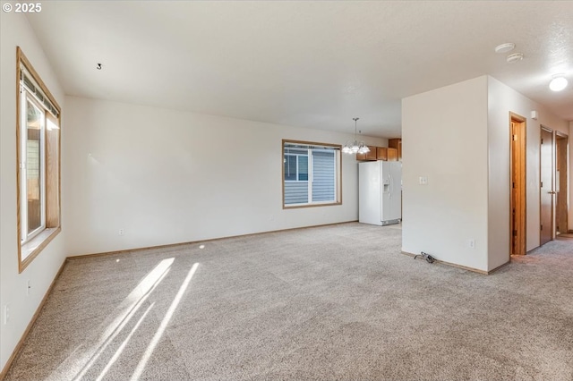 unfurnished living room with light colored carpet and an inviting chandelier