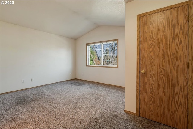 carpeted spare room featuring vaulted ceiling