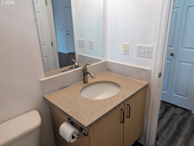 bathroom with toilet, hardwood / wood-style flooring, and vanity