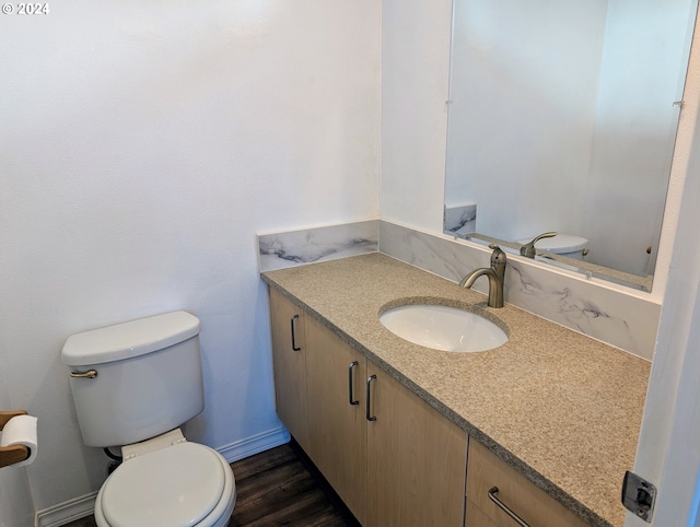 bathroom with baseboards, vanity, toilet, and wood finished floors