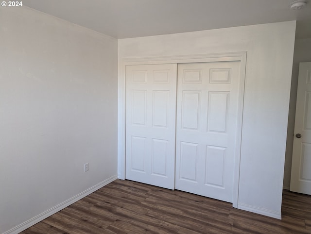 unfurnished bedroom featuring dark wood-type flooring and a closet