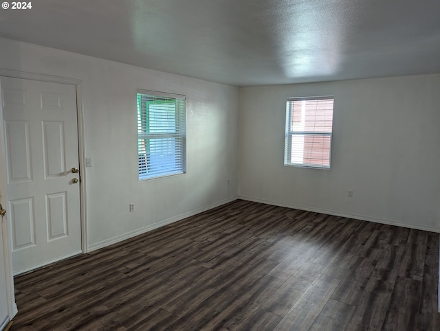 unfurnished room featuring dark wood-style flooring and baseboards